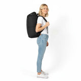 Kvinde i hvid T-shirt og jeans med en sort Zeeksack-rygsæk, set fra siden.