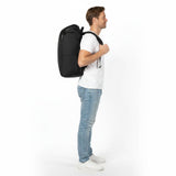 Mand i hvid T-shirt og jeans med en sort Zeeksack-rygsæk, set fra siden.