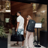 Zeeksack - Kvinde med The Organizer 30L på ryggen og mand med The Weekender 50L i hånden på vej ind på et hotel.