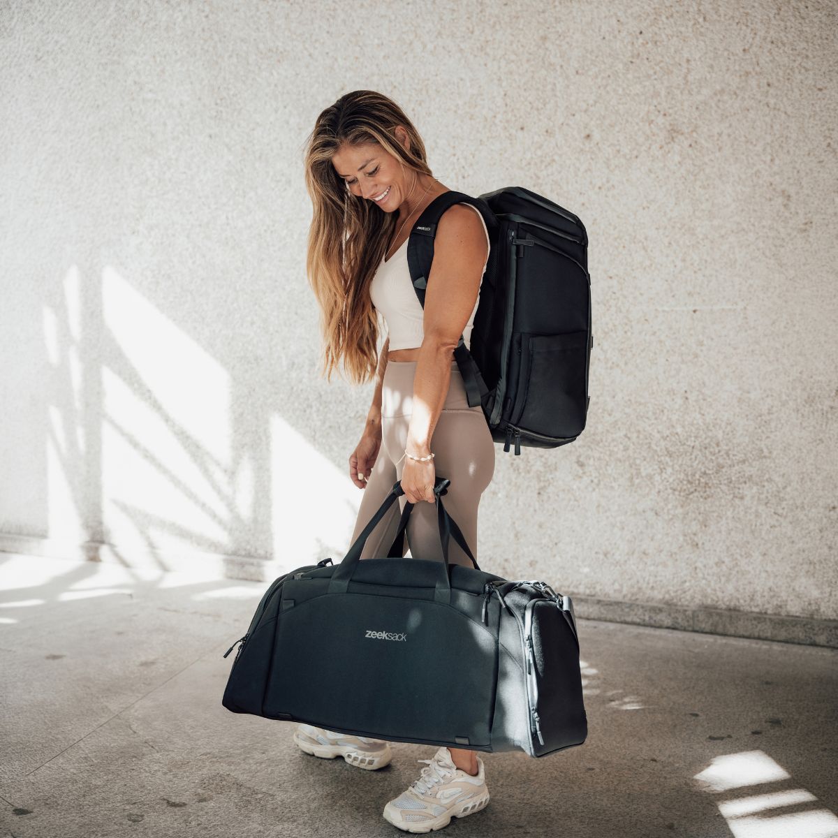Zeeksack - Kvinde med The Organizer 30L på ryggen og The Weekender 50L i hånden.